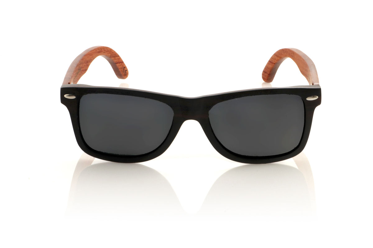 Wood eyewear of Ebony OSCAR. Gafas de sol de madera OSCAR, destaca su estilo inspirado en los clásicos, ofreciendo una silueta ancha que capta la atención. Estas gafas están meticulosamente fabricadas en capas de madera laminada, combinando ébano en el exterior y caoba en el centro, creando un efecto visual único y elegante, realzado por remaches plateados en el frontal. Las varillas de caoba prometen no solo estilo, sino también una durabilidad excepcional. Además de su diseño impecable, las OSCAR garantizan una visión clara y una protección total, asegurando que tus ojos estén protegidos con el máximo confort. Medidas: 149x45 mm. Calibre: 54. Con las OSCAR, experimentarás la perfecta unión entre moda y funcionalidad. for Wholesale & Retail | Root Sunglasses® 